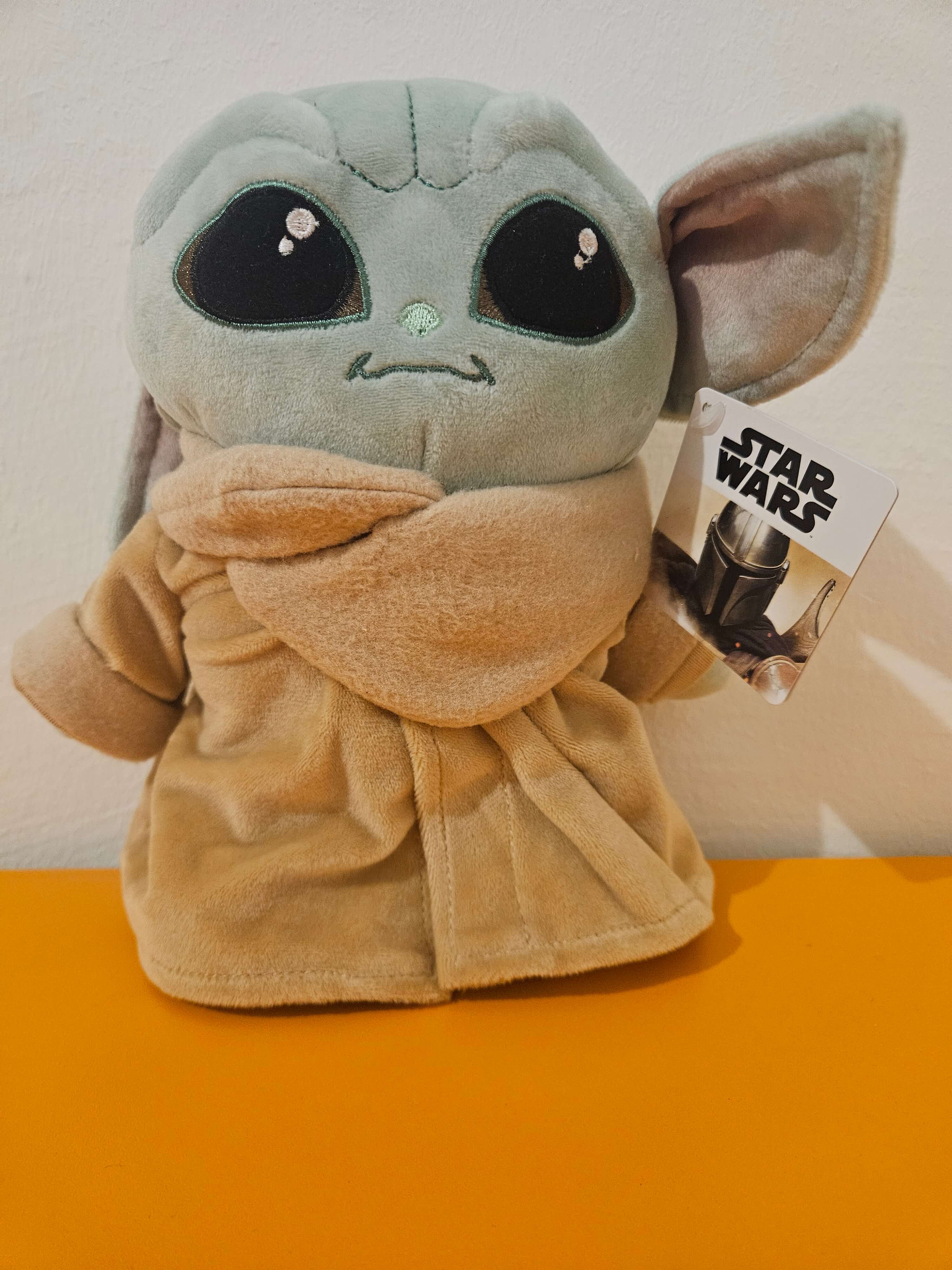 Plush toy resembling a character from 'Star Wars' on an orange surface with a neutral background